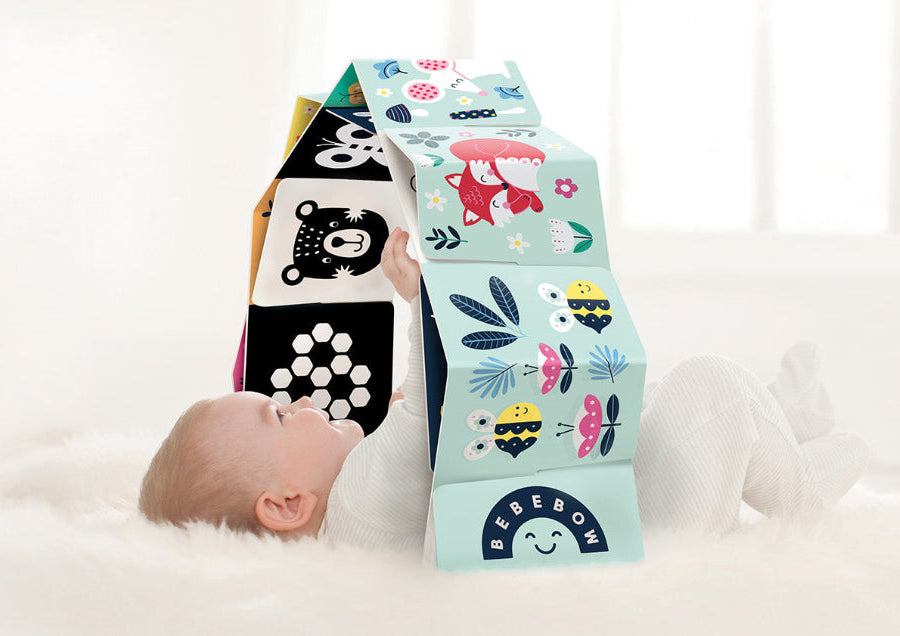 Baby playing with the baby sensory arch on a white fluffy rug
