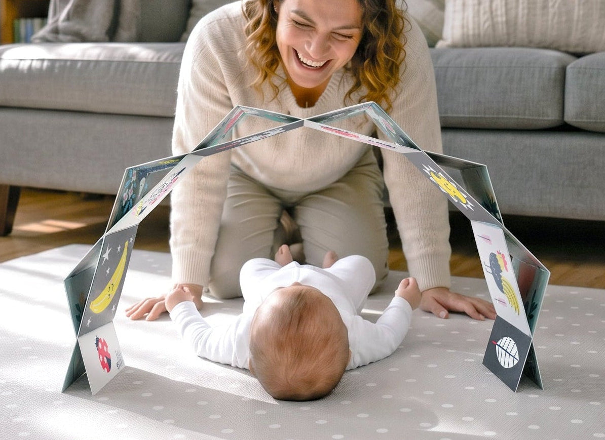 Woman playing with a baby and the baby arch on a matt in a living room.